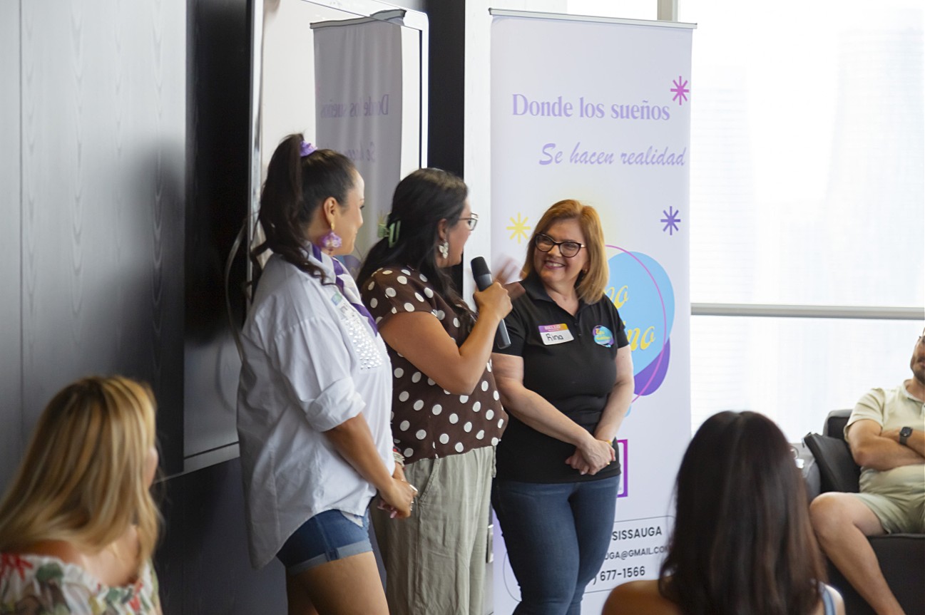 Emprendedoras latinas posando frente al banner del evento